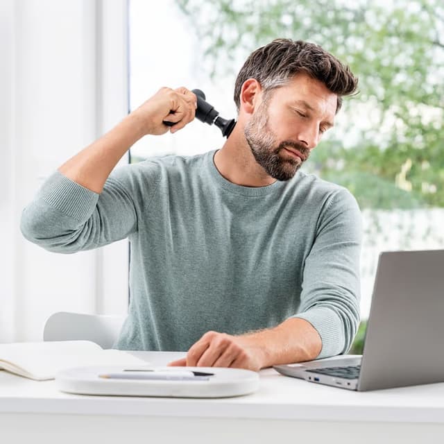 homme qui se masse le cou avec un pistolet de massage
